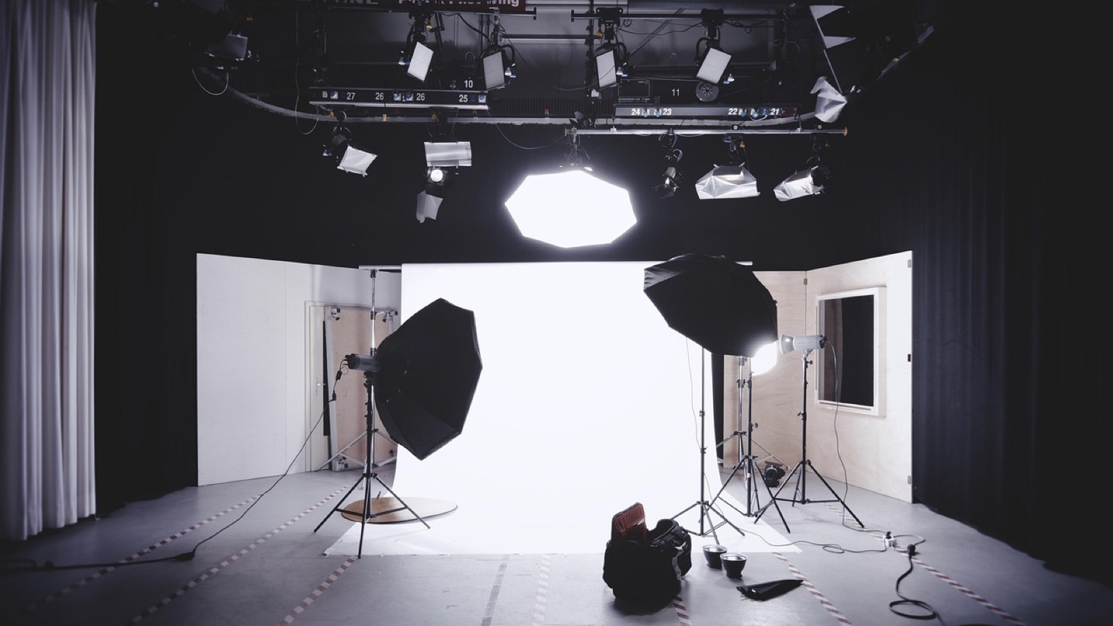 Estudio fotográfico vacío con fondo blanco de papel, dos softboxes octagonales sobre trípode y luces colgadas del techo