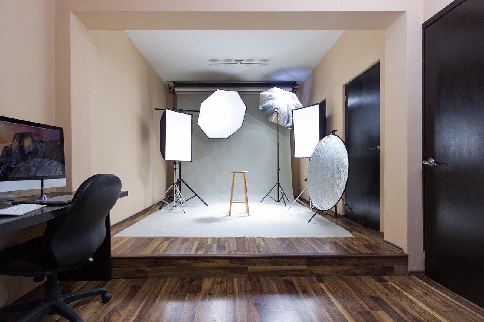 Estudio con fondo blanco, dos softboxes, un reflector redondo y un banco de madera al centro